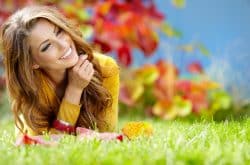 A woman smiling and laying on the ground outside