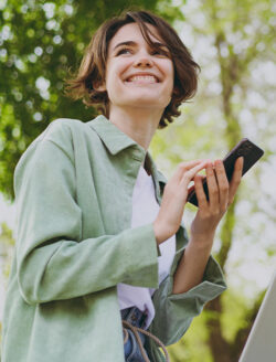 A young woman smiling and walking with her phone in her hand